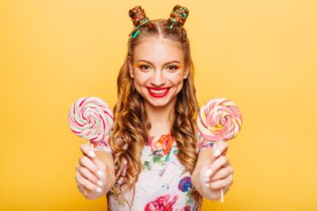 Smiling lady holding two huge colorful lollypops