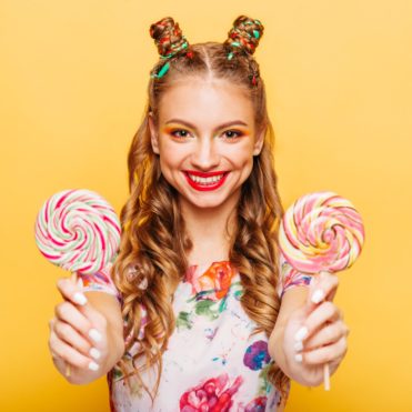 Smiling lady holding two huge colorful lollypops